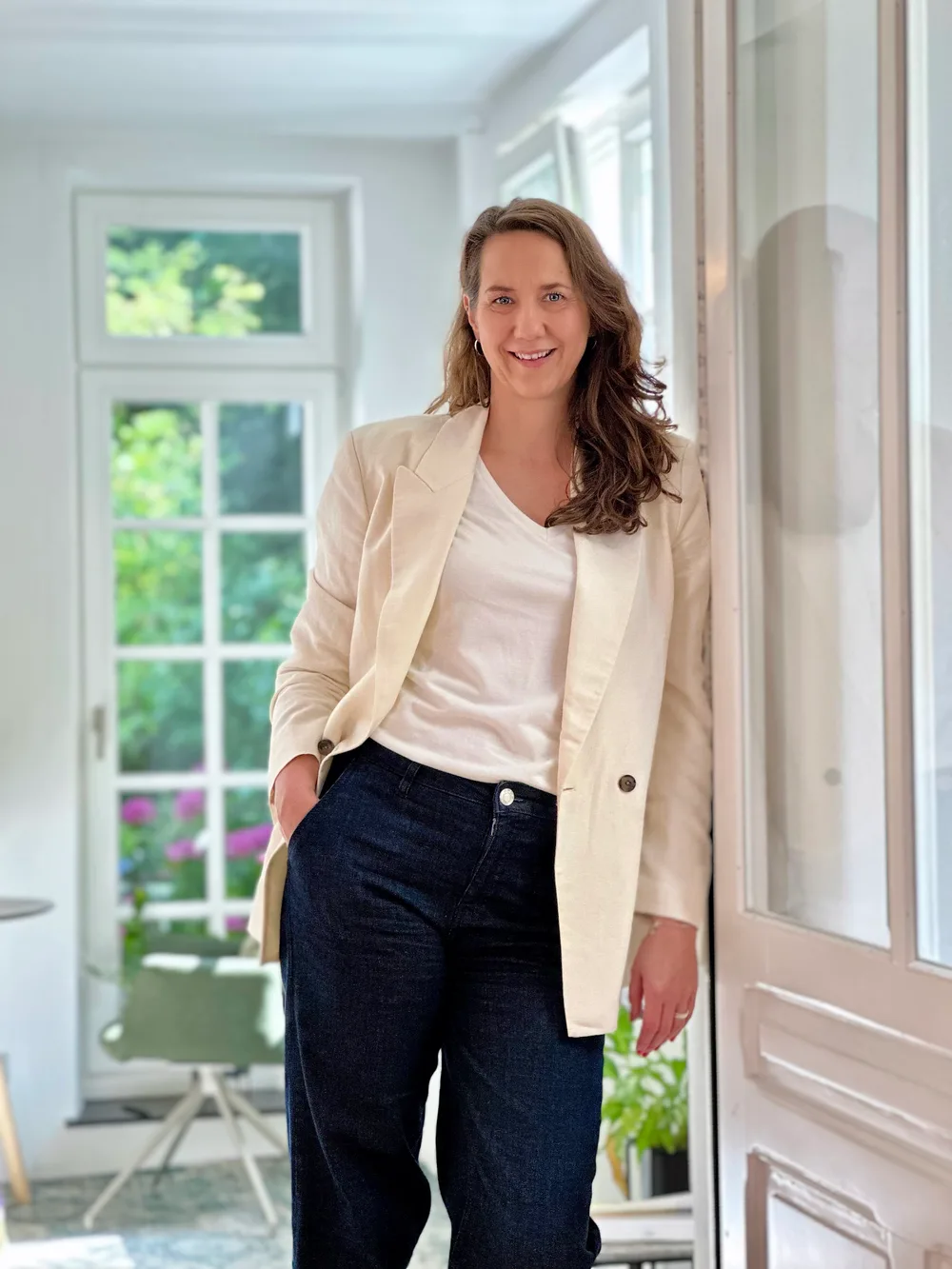 Ramona Franke lehnt lächelnd in einem hellen Raum an einer Fensterfront